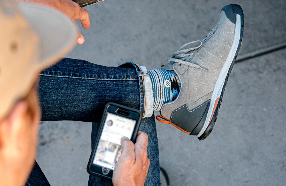 Man checking Instagram in his Oboz Bozeman Low Leather casual shoes.