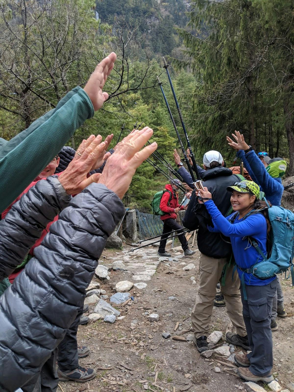 Group of hikers cheering one another on along the trail with their trekking sticks.