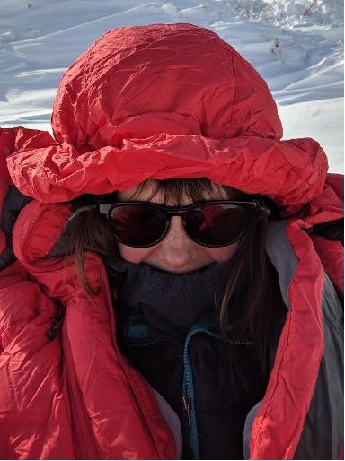 Woman staying warm in winter conditions in a red parka jacket
