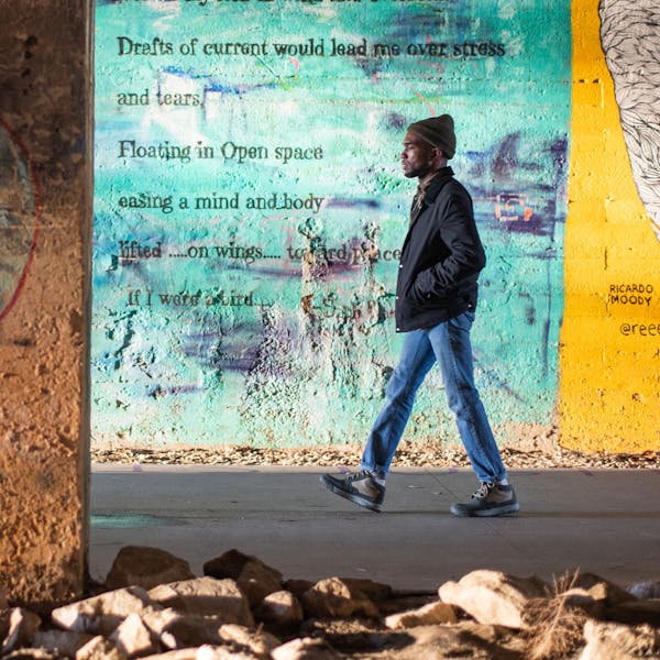 Man walking in front of a bright graffiti wall wearing Oboz Burke Chukka shoes