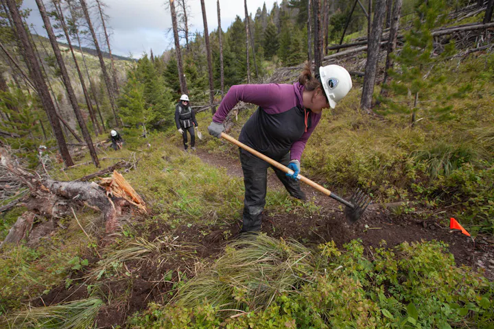 A member of the Oboz team doing trail work with a McLeod on their adopted section of the CDT.