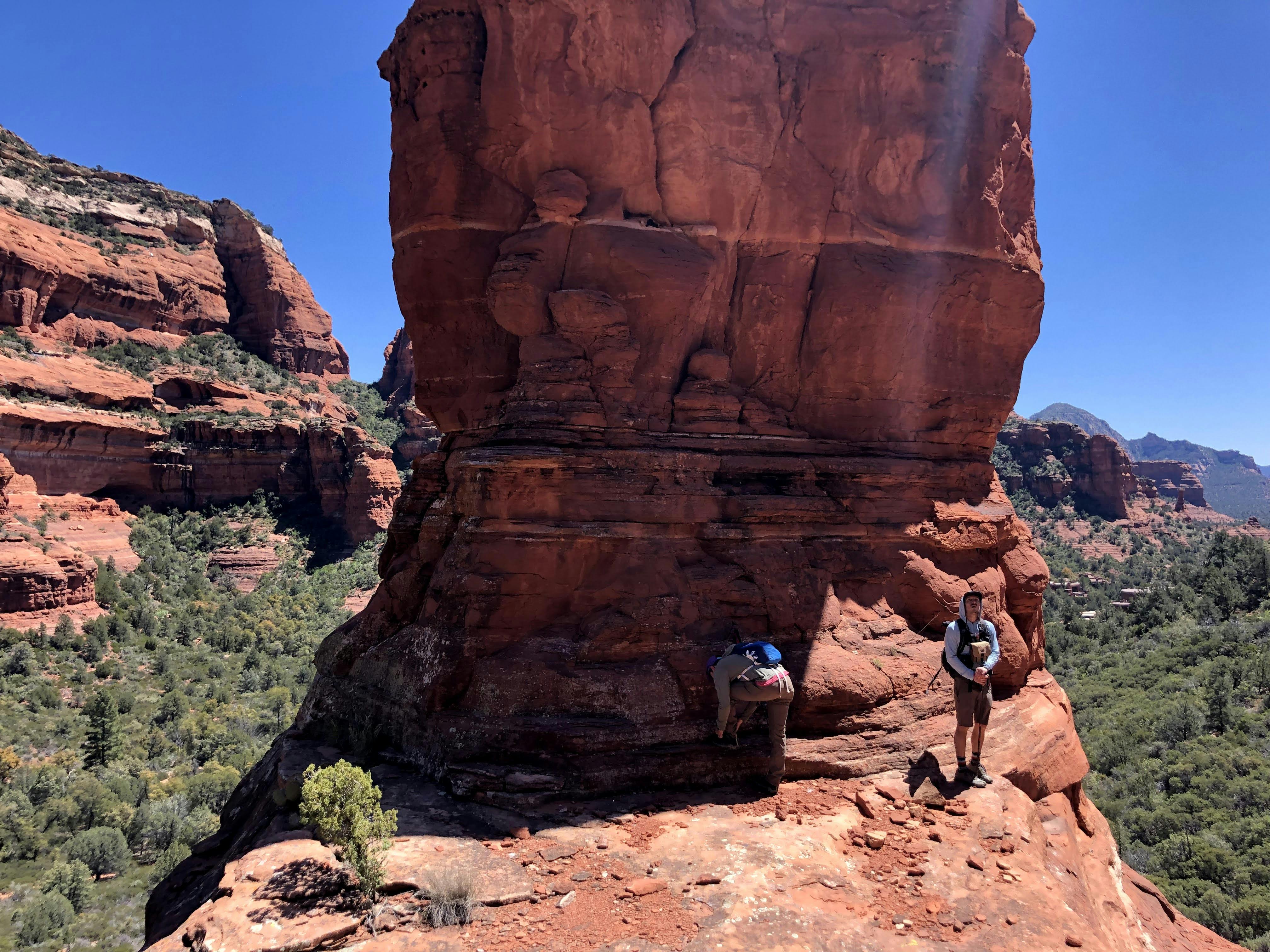 Two hikers stand next to a large rock formation in the canyon