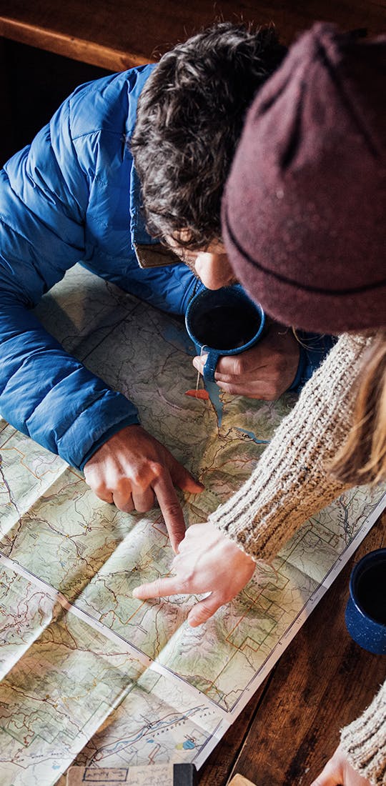 Two people planning their hiking route using a physical map.