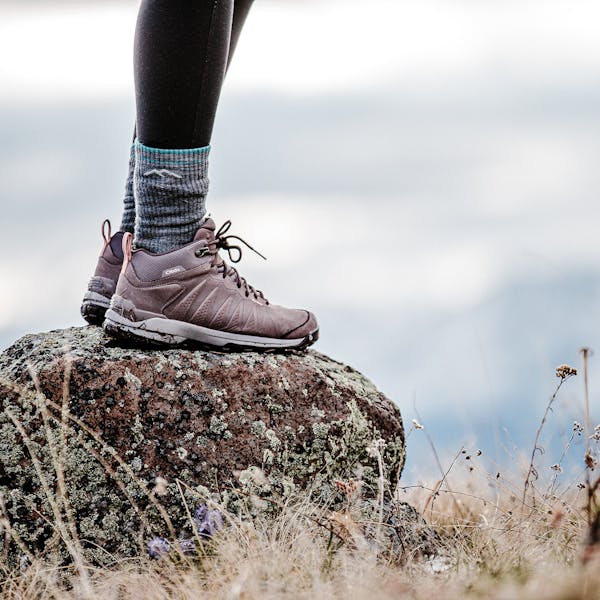 Person standing on a rock wearing the women's Oboz Sypes Mid boots.