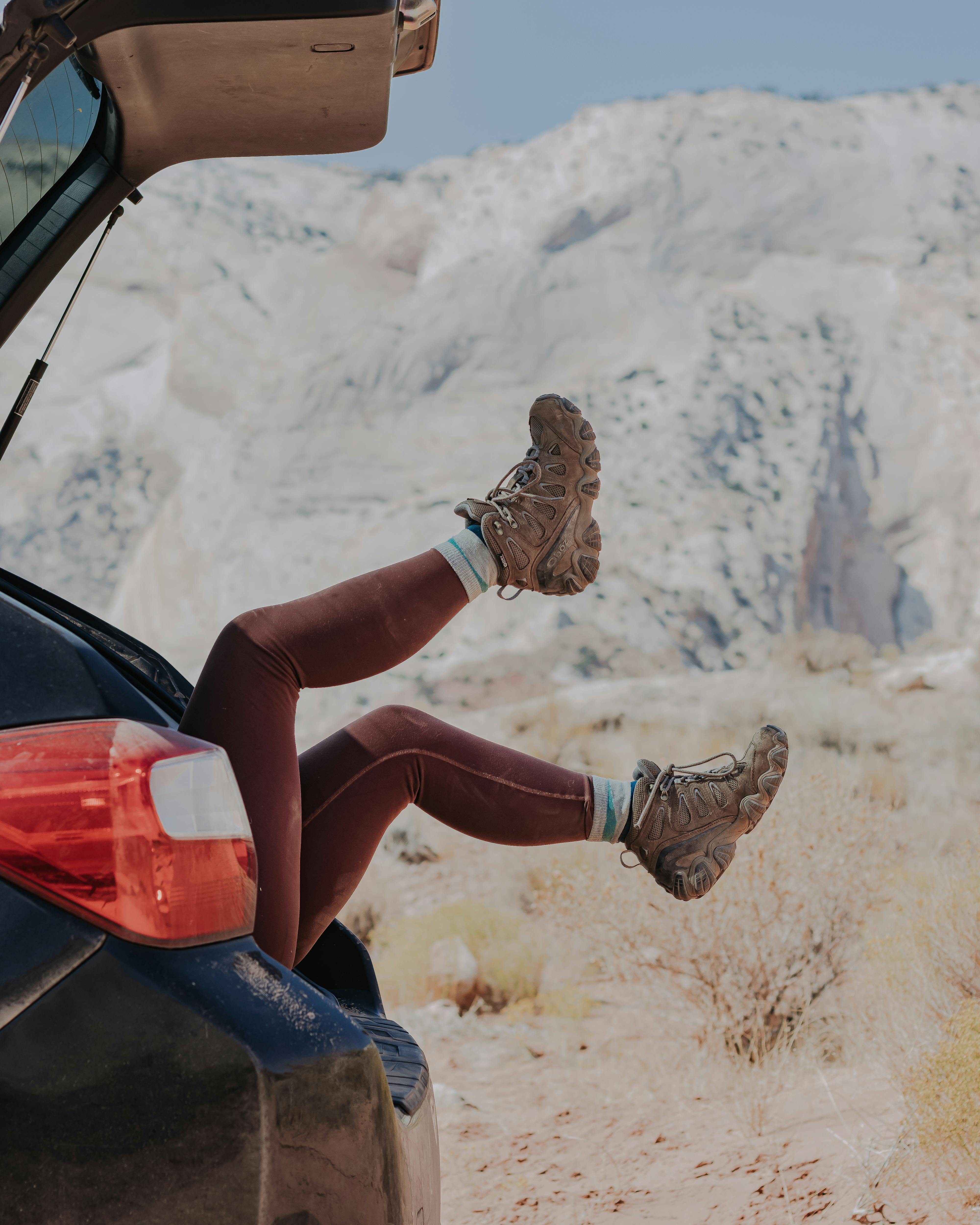 Woman lying in the back of car trunk in her Oboz Sawtooth Mid hiking shoes.
