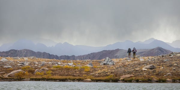 Two hikers wearing Oboz Bridger Mid hiking boots heading into a storm in the high Colorado alpine.