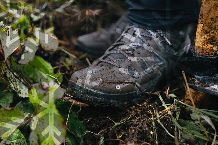 A pair of Oboz Sawtooth X hiking boots in muddy terrain