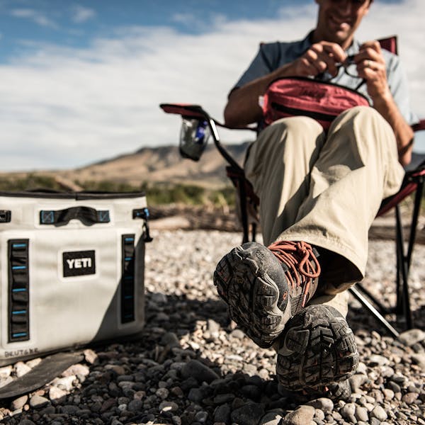 Man relaxing in a camp chair wearing the Oboz Firebrand II Low B Dry shoes.
