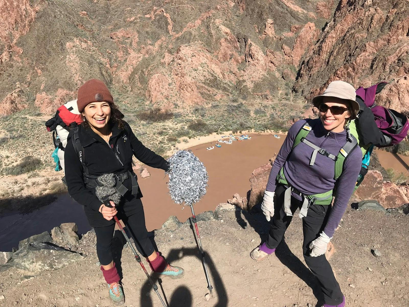 Two hikers standing on a cliff overlooking the Grand Canyon