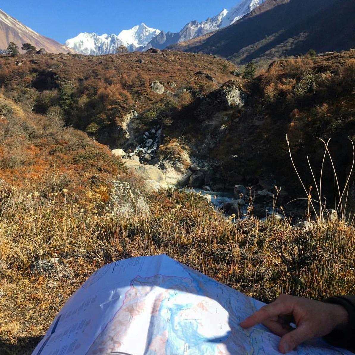 A person viewing a map while navigating the trail with peaks in the background