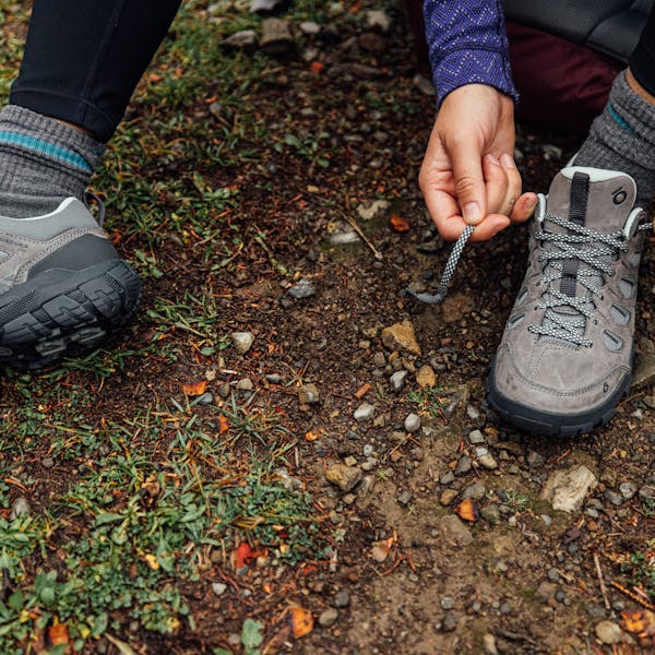 A hiker lacing up the Sawtooth X Low hiking shoes on the trail.