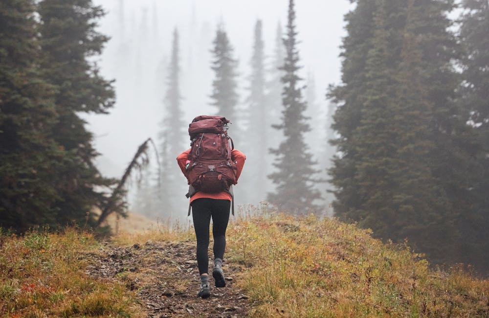 A woman backpacks through the fog in Oboz hiking boots