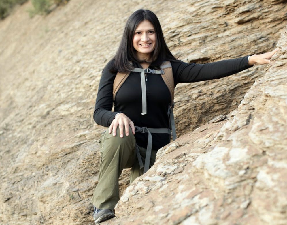 Karla Amador standing along a rock wall wearing Oboz hiking shoes
