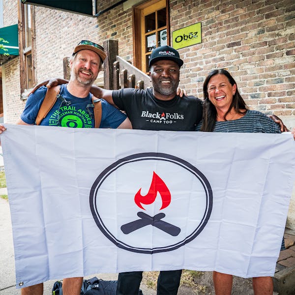 Amy Beck of Oboz Footwear and Earl Hunter of Black Folks Camp Too posing with a Unity Blaze logo flag.
