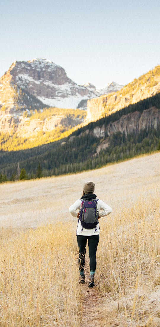 Woman hiking in a mountain meadow wearing Oboz mid hiking boots