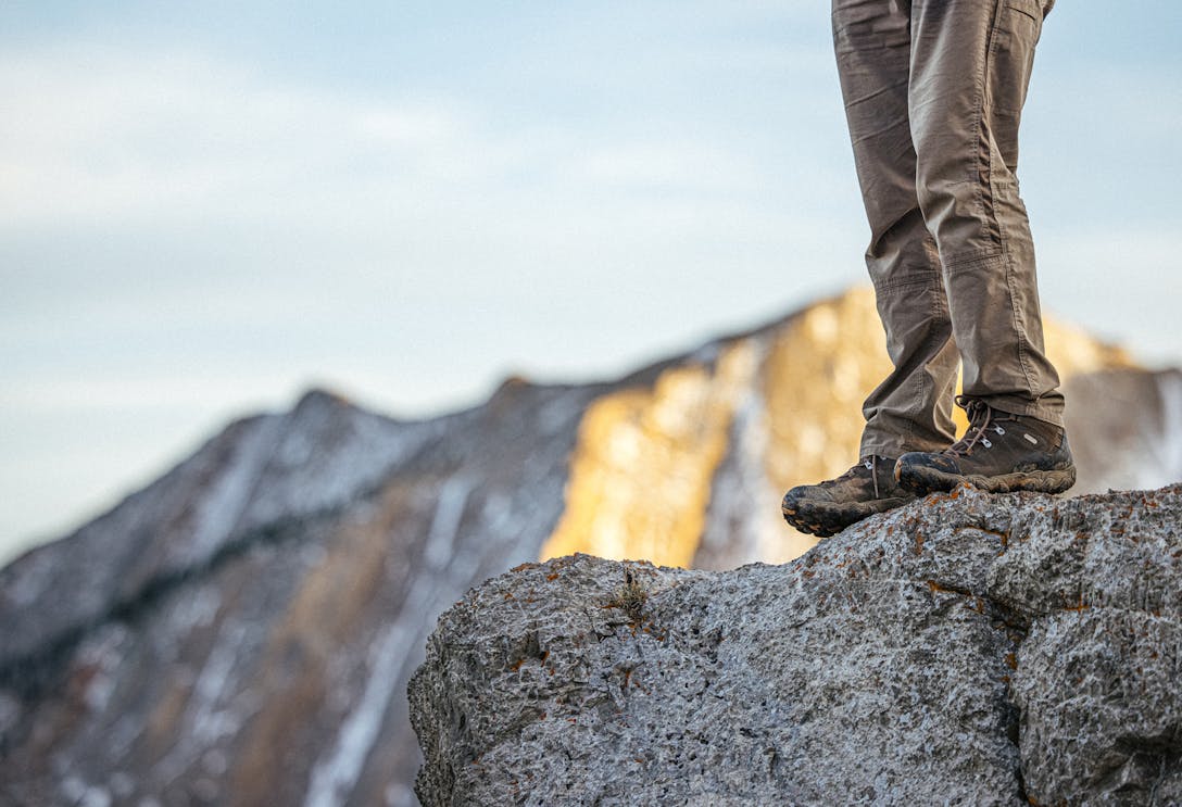 A person standing in the Oboz Bridger Mid hiking boot on a rocky ledge.