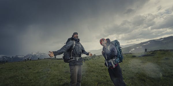 Two backpackers enjoying the rainy and cloudy weather while out on an adventure.
