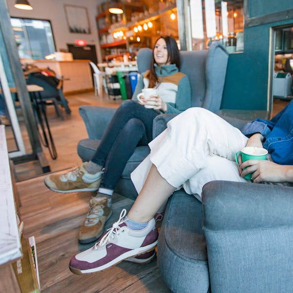 Women sitting in coffee shop wearing Oboz Emma Lows casual shoes.
