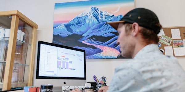 Oboz employee working on a mac computer with cool art in the background