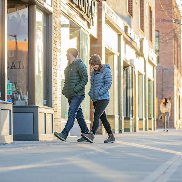 A couple strolls through downtown Bozeman while staying warm in puffy jackets and Oboz insulated boots.