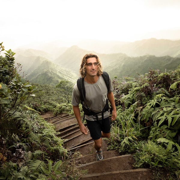 Man hiking up a forest pathway in a lush forest environment while wearing Oboz hiking shoes.