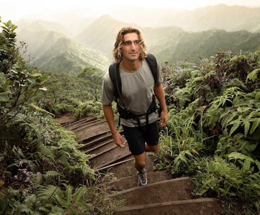 Man hiking up a forest pathway in a lush forest environment while wearing Oboz hiking shoes.