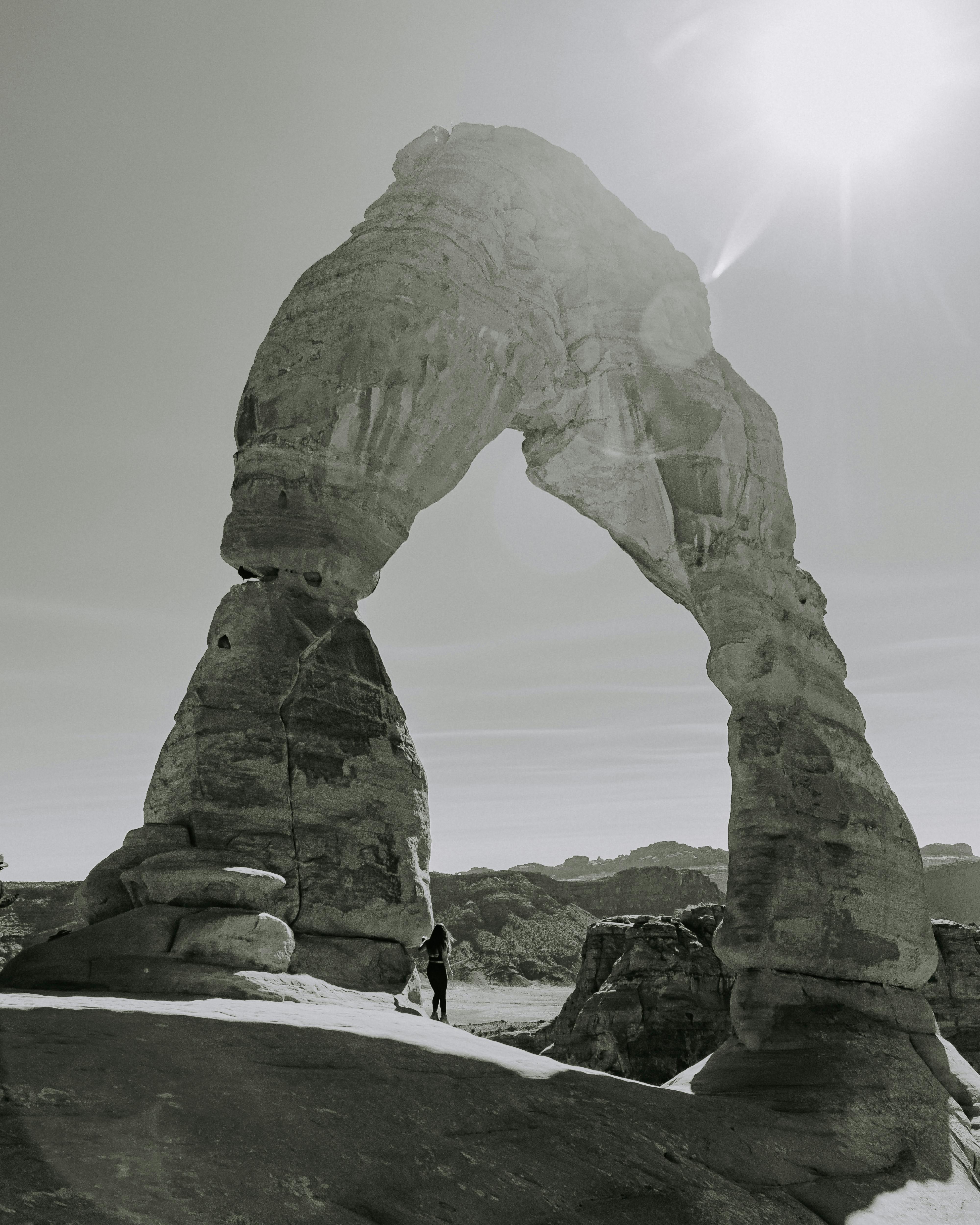 Woman standing below Delicate Arch in Arches National Park.