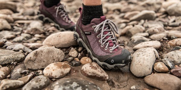 Women's Oboz Firebrand hiking shoes worn in a rocky riverside. 