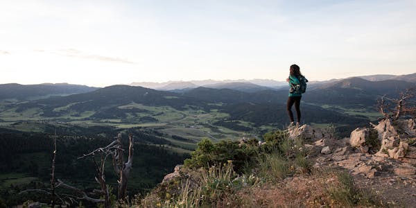 Woman in Oboz hiking boots gazing over a mountain landscape while out day packing.
