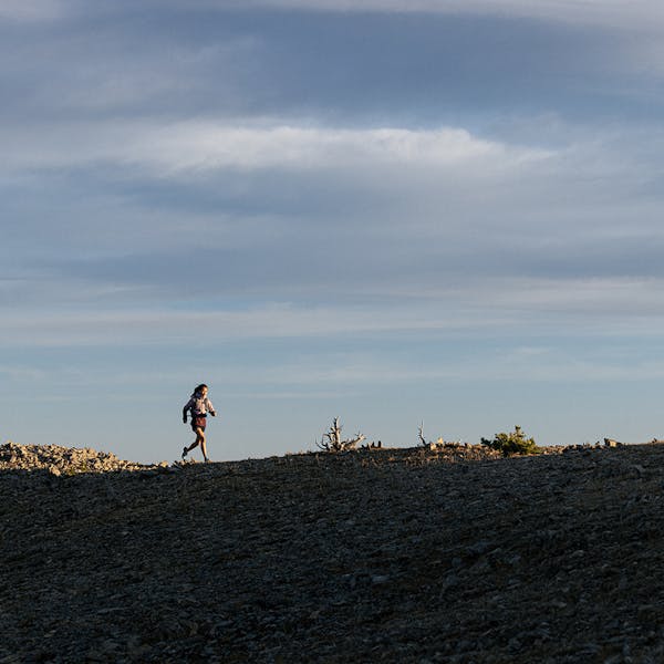 Person quickly hiking on a mountain ridgeline.