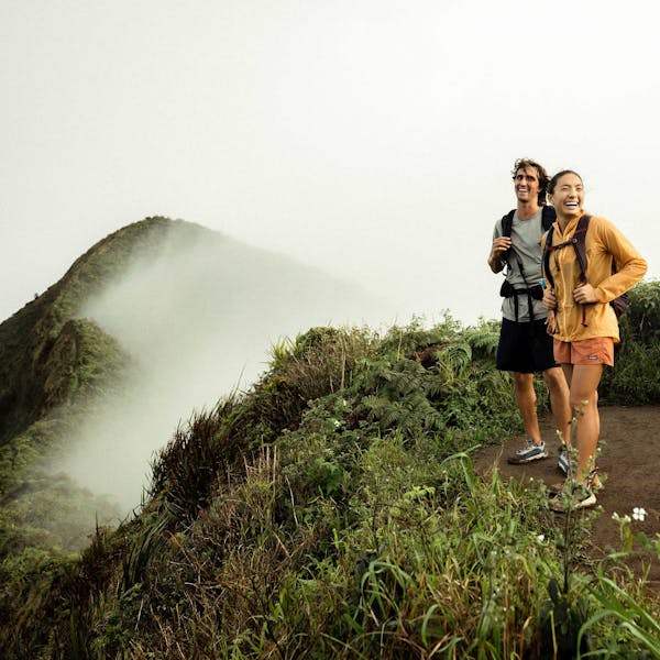 Two hikers in the Oboz Cottonwood Low at the top of a mountain top in the lush Hawaiian forest. 