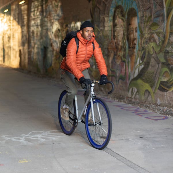 A man rides a bike through a tunnel wearing Oboz Beall casual shoes.