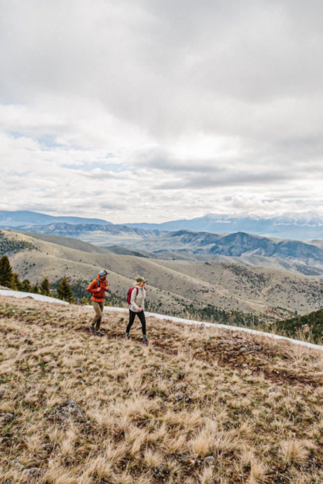 Two hikers on a trail wearing Oboz Hiking shoes with mountain ranges in the background