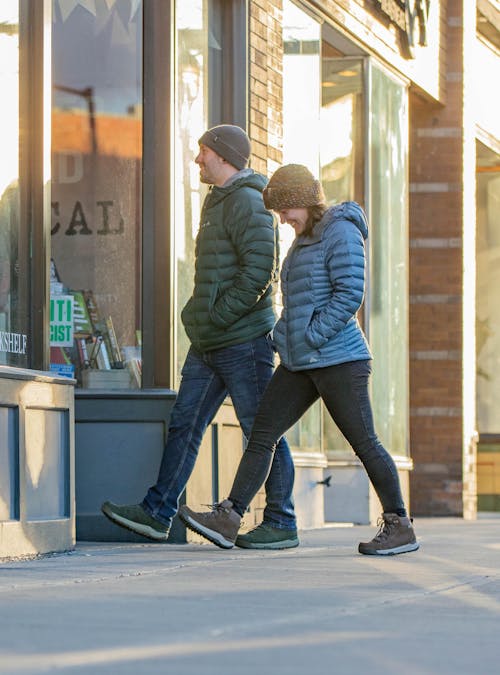 A man and woman stroll down a sidewalk in Oboz winter hiking boots.