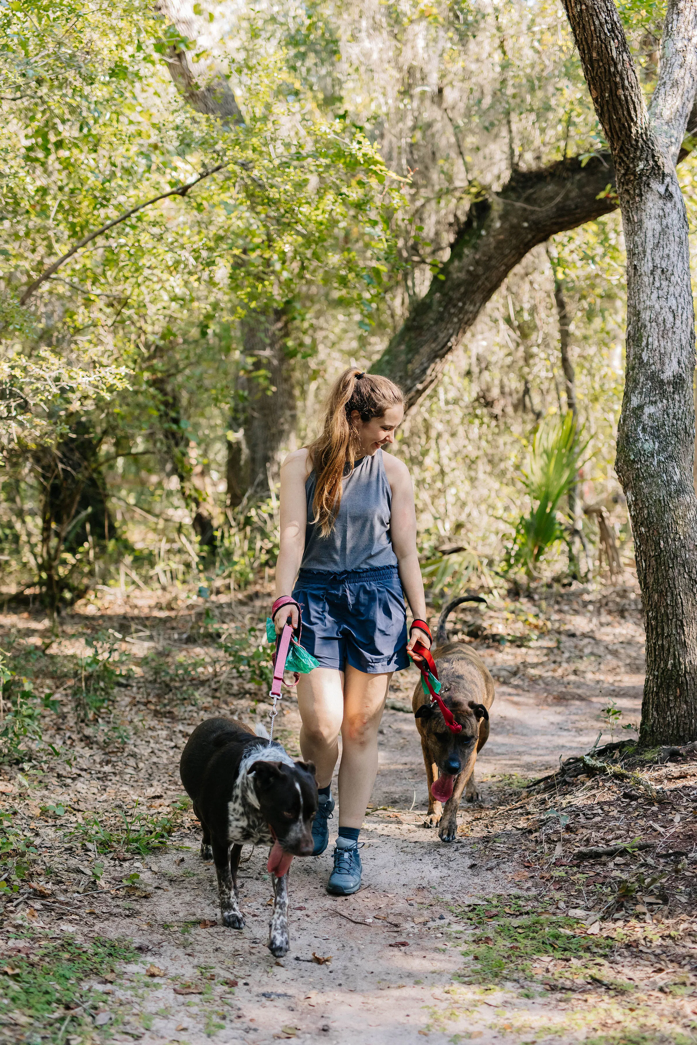 Woman hiking on trail in the Arete Low hiking shoes with two dogs