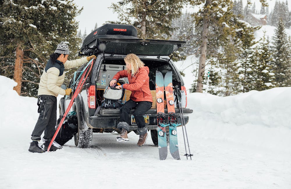 Couple prepares their ski's and backpack's for a backcountry adventure in the mountains while wearing Oboz winter boots.