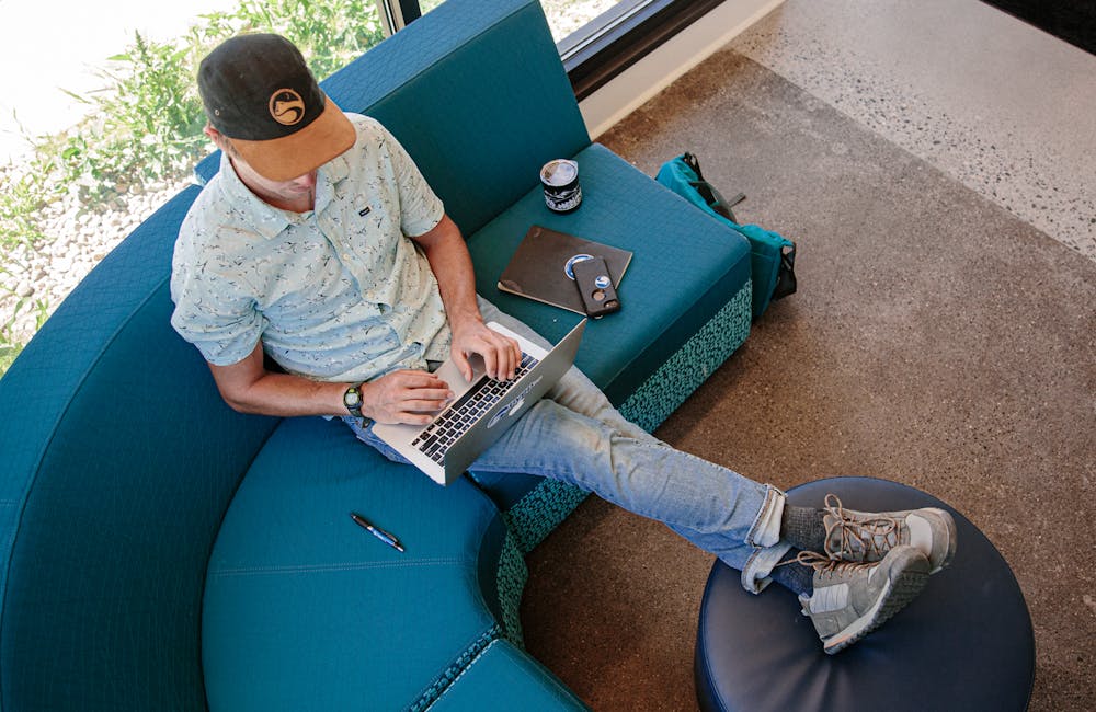 A man works on a laptop in Oboz Bozeman casual shoes.