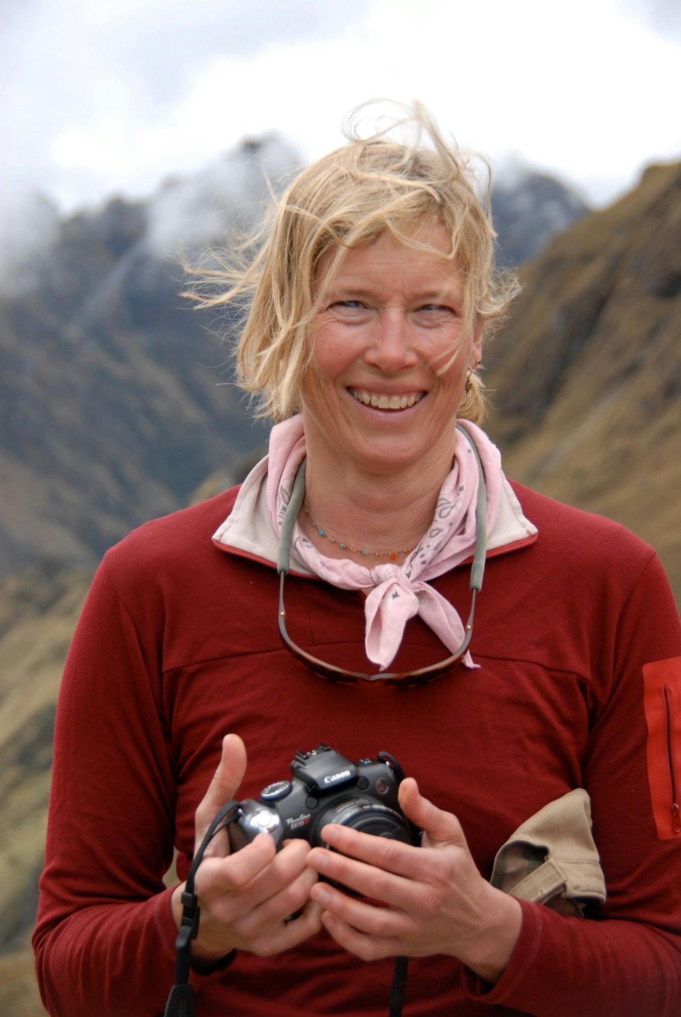 Jennifer Royall smiling while holding a camera in the mountains.