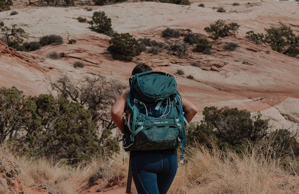 Woman backpacking on desert trail in Oboz hiking shoes while visting Arches National Park.