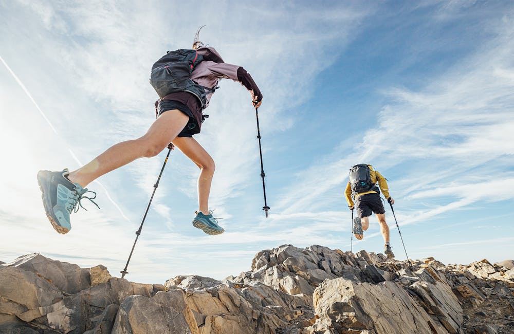 Woman jumping over rocks on a hiking trail while wearing Oboz Katabatic hiking shoes