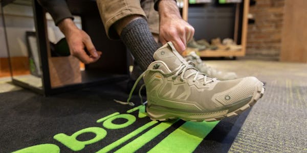 A person puts on an Oboz Katabatic hiking boot at a retail store. 