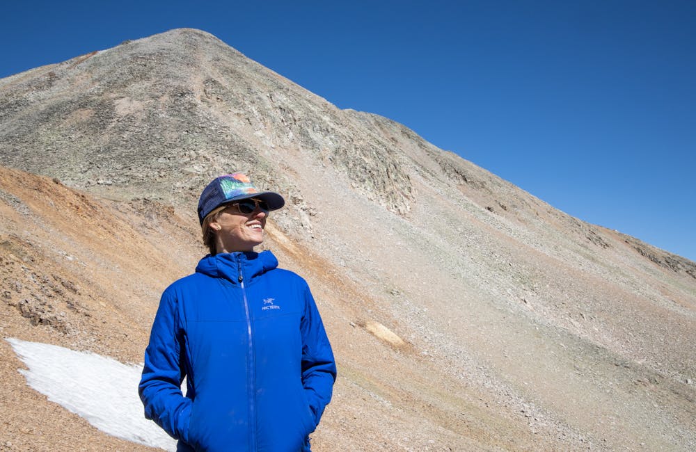 Hiker posed in front of a mountain top with blue skies in the background