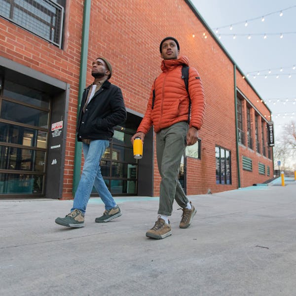 Two men walk in front of a brick building wear the Oboz Burke Chukka and Beall Low casual shoes.