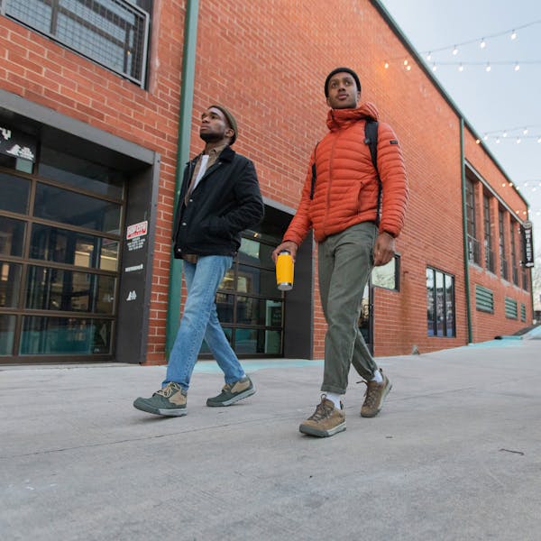 Two men walk in front of a brick building wear the Oboz Burke Chukka and Beall Low shoes