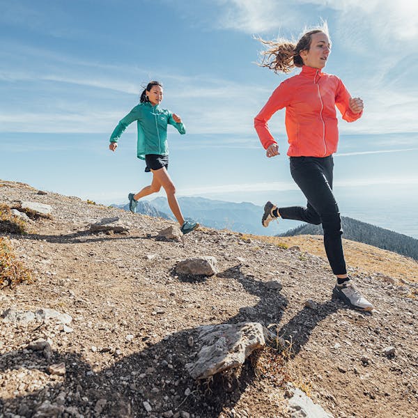 Two women trail running in the Katabatic Low hiking shoes.