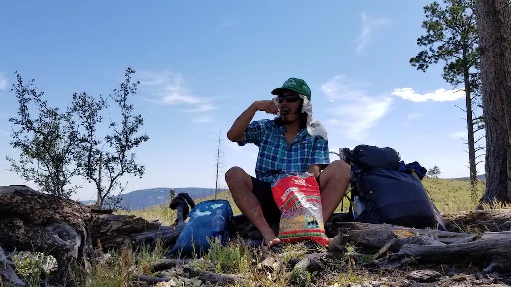 Tyler eats a meal while on a backpacking trip