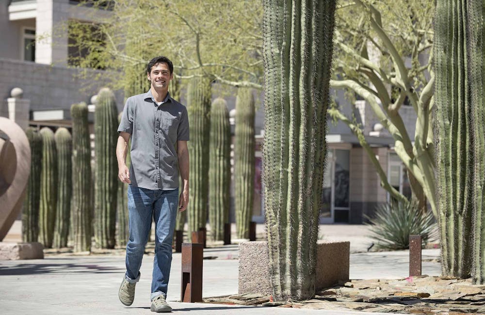 A man walking by a cactus on a sidewalk while wearing Oboz Whakata Town Casual Sandals