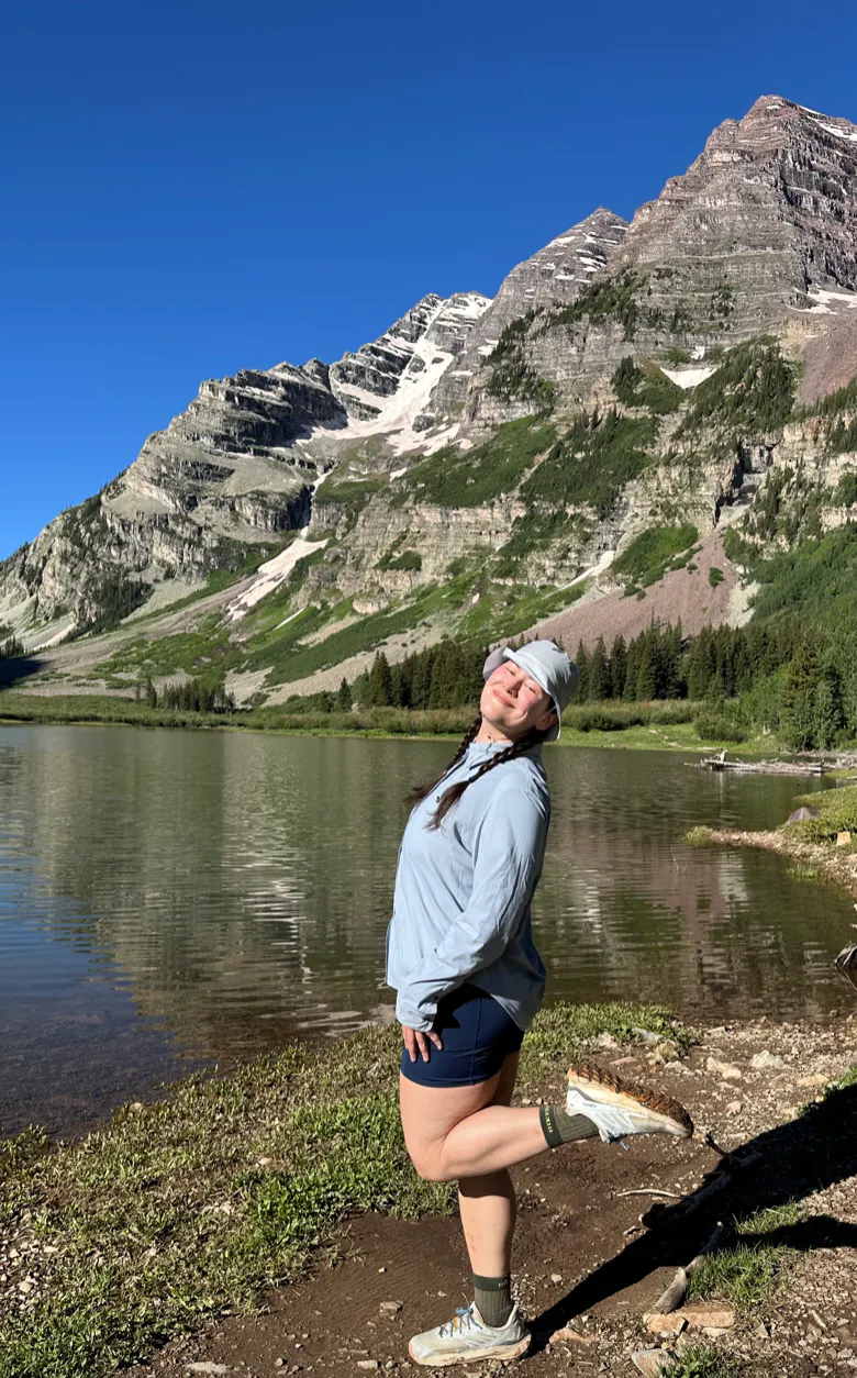 Kylie standing by a mountain lake after a day on the trail.