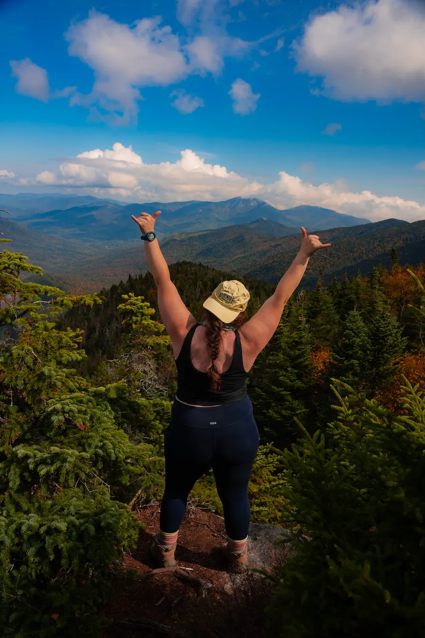 A hiker celebrates after successfully summiting a peak in the Adirondack Mountains.