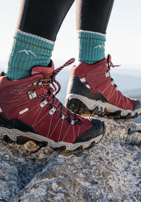 Oboz Women's Sawtooth II hiking boots at the top of a mountain peak.